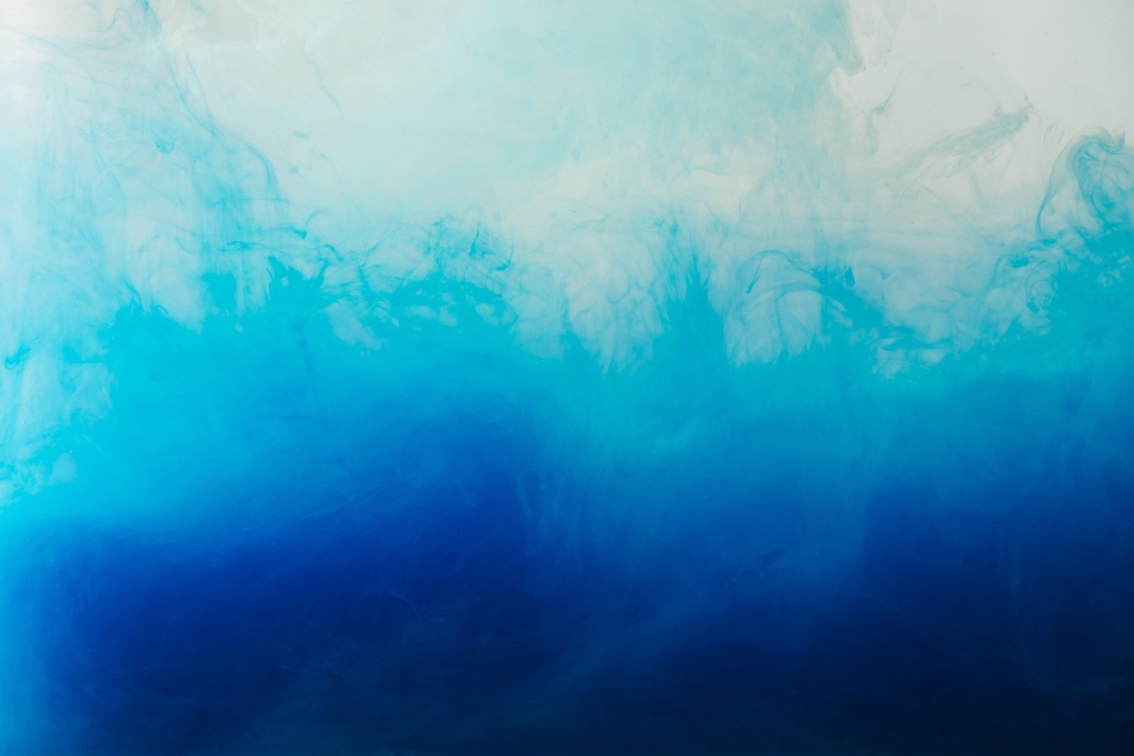 close up view of mixing of blue and turquoise paints splashes in water